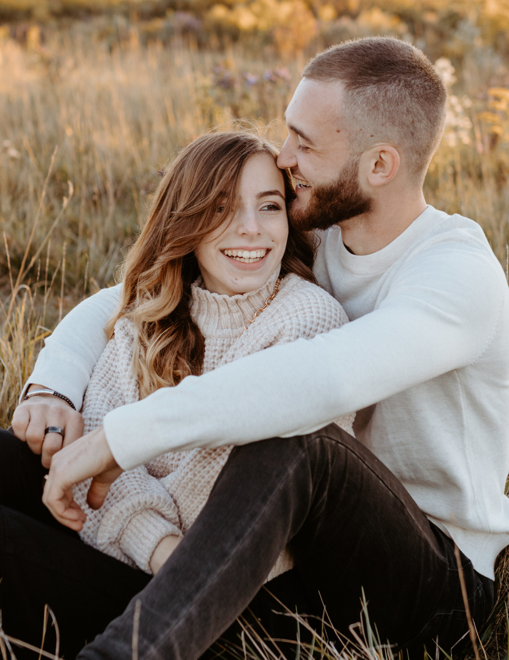 A woman sitting in her boyfriend's lap, snuggled up close and laughing together.