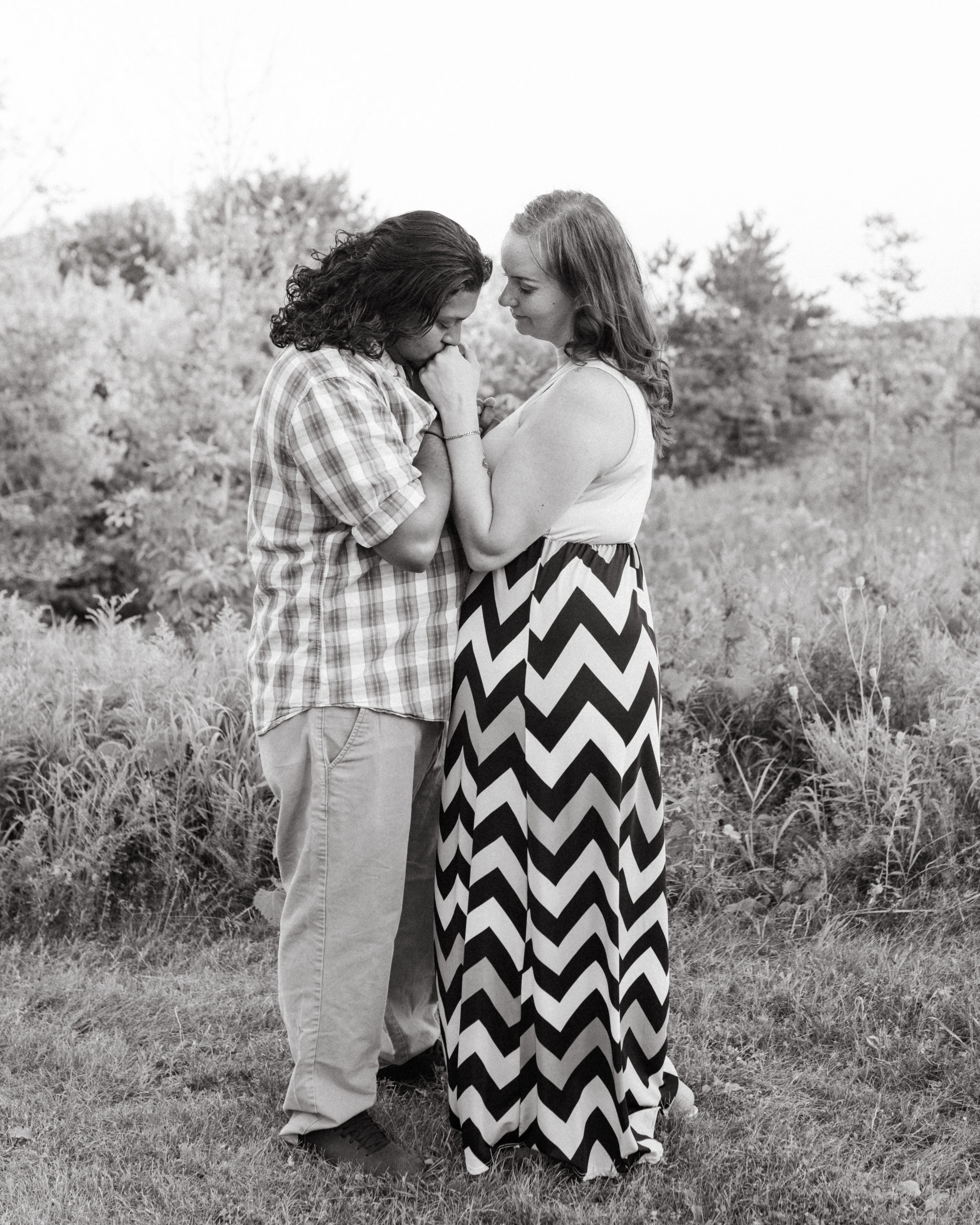 A black and white photo of a man kissing his girlfriend's hand.